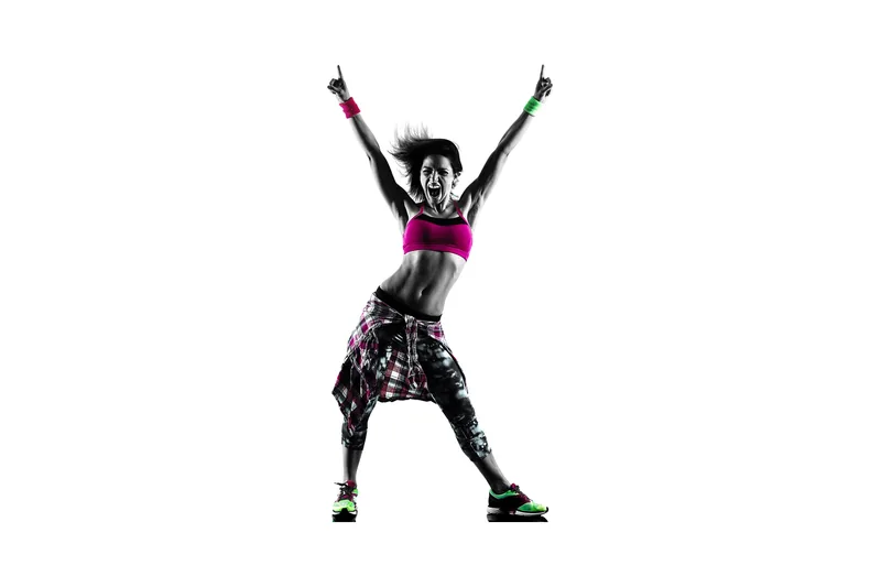Femme qui danse avec énergie, bras levés, chemise nouée à la taille.