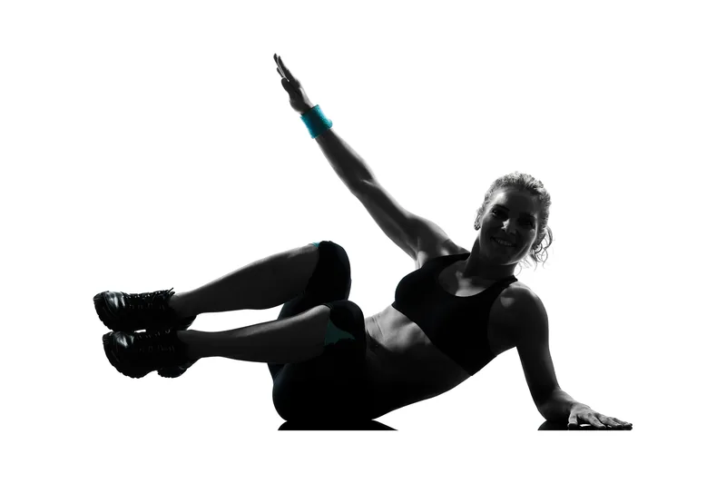 Silhouette d'une femme qui fait un exercice d'abdominaux au sol, bras levé.