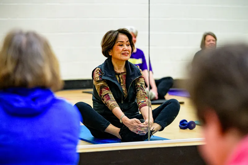Participante souriante assise sur son tapis pendant les étirements.